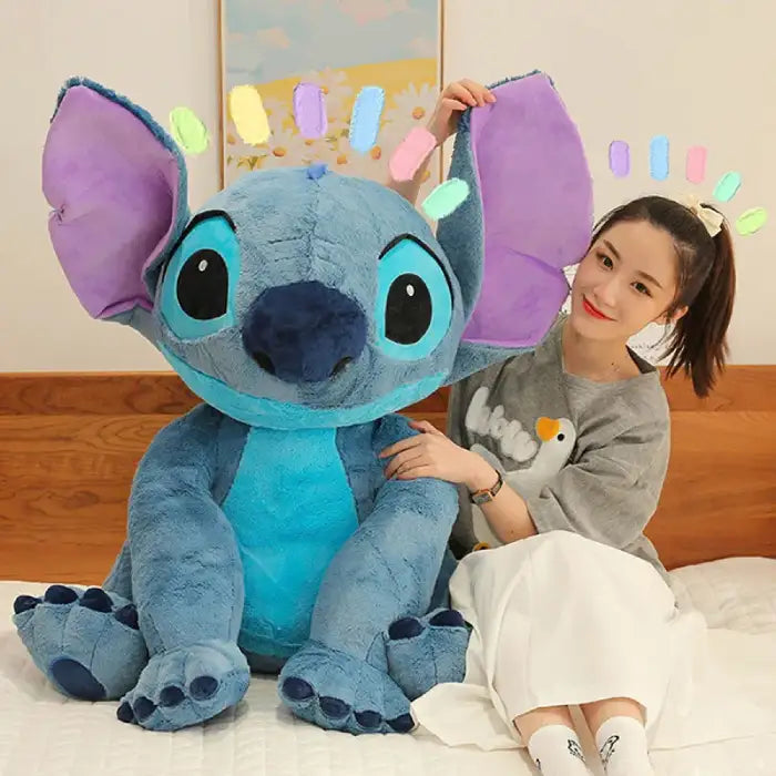 lilo & Stitch large blue plush toy with girl on bed holding up its ears