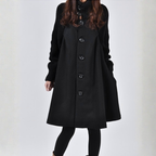 Long trench coat in black with oversized buttons and knit sleeves for a modern, winter-ready style.