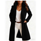 Long wool coat in black with double-breasted design and wide lapels styled over white outfit.