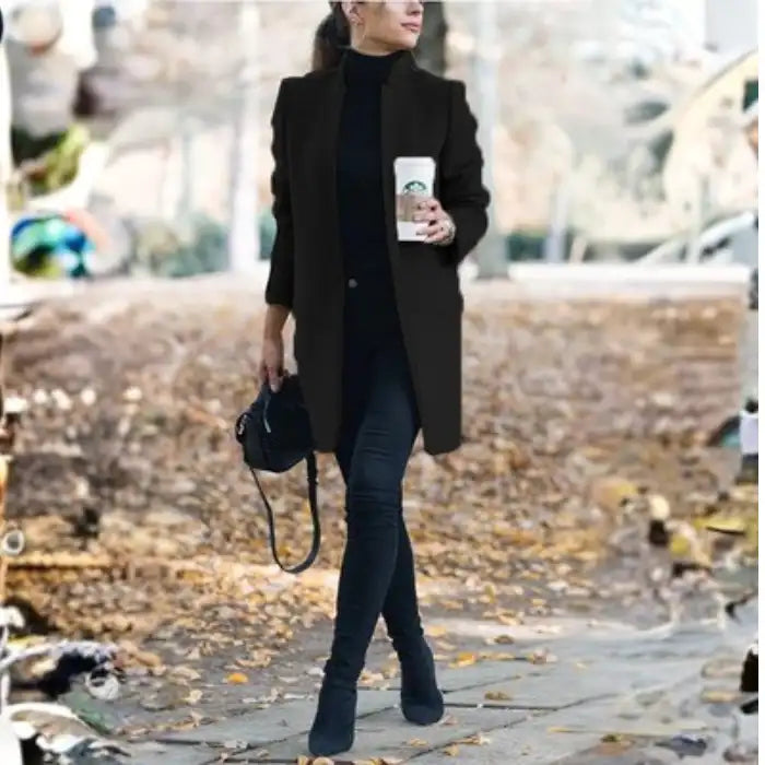 longline coat women in black walking outdoors holding coffee in a fall setting
