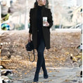longline coat women in black walking outdoors holding coffee in a fall setting