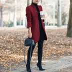 longline coat women in deep red walking outside with coffee and black handbag