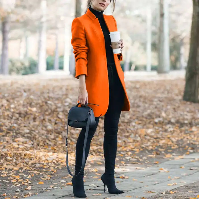 longline coat women in bright orange holding coffee outdoors in fall leaves