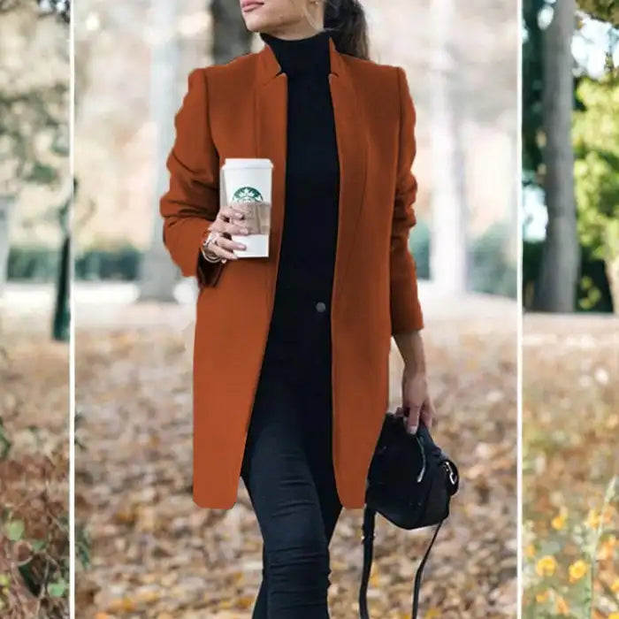 longline coat women in rust orange standing outside with coffee and black handbag