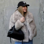 Luxury faux fur coat in beige styled casually with cap and jeans, highlighting soft plush texture and relaxed warm winter outerwear