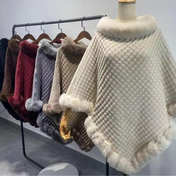 Luxury Fur-Trimmed Knit Poncho collection hanging neatly on rack, showcasing assorted winter colors and soft fur-trimmed knit design