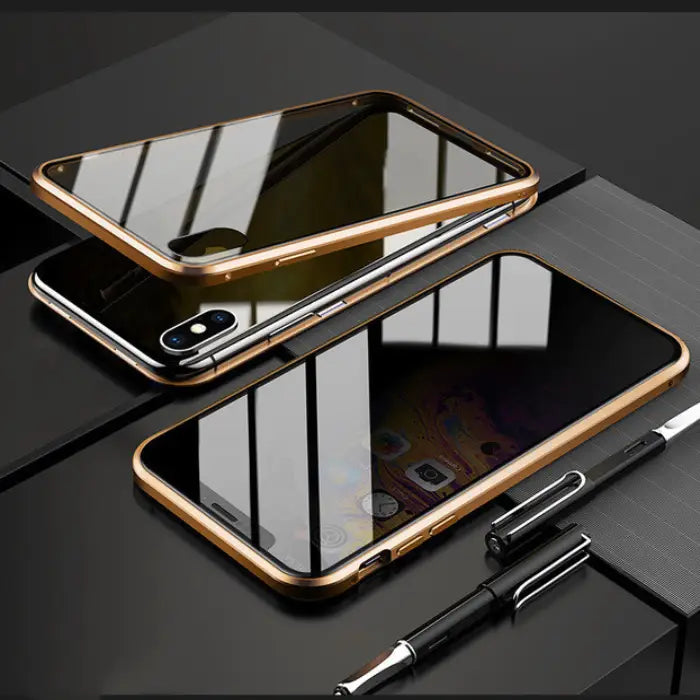 Gold-framed magnetic iPhone case with a reflective mirror design placed on a desk with pens.