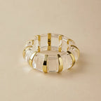 marbled acrylic bracelet in clear translucent design with gold accents displayed on soft tan surface