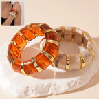 marbled acrylic bracelets in amber and cream tones with gold accents shown together on beige background