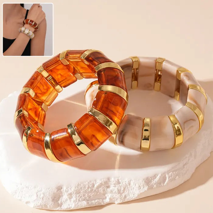 marbled acrylic bracelets in amber and cream tones with gold accents shown together on beige background