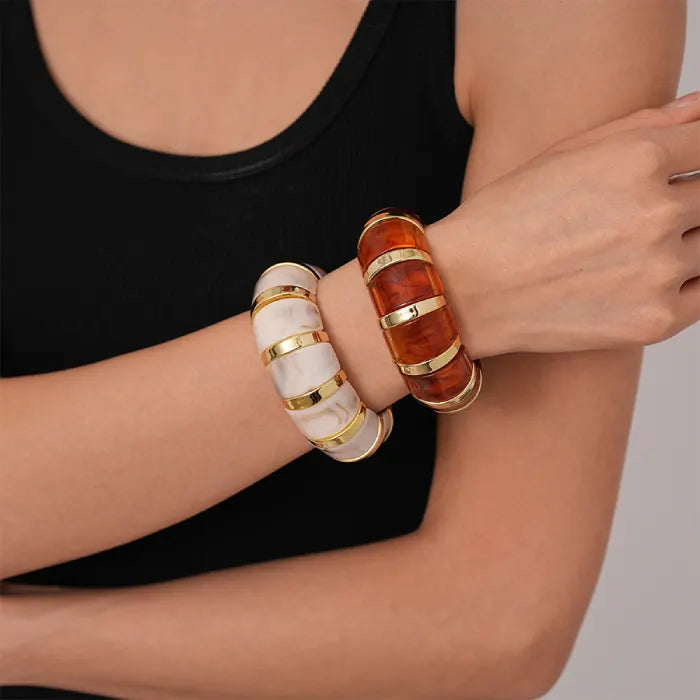 marbled acrylic bracelets in contrasting amber and cream tones stacked on wrist with gold detailing