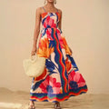  Maxi dress with vibrant floral print and spaghetti straps, styled for beachwear with straw handbag.