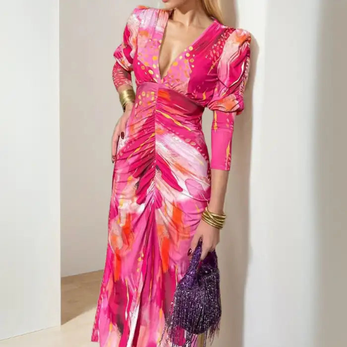 Maxi dress with ruched front, puff sleeves, and bold pink-orange abstract print with deep v-neckline.