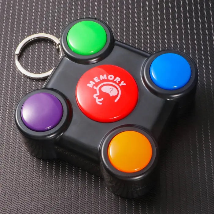Close-up of memory game toy with red center and four colorful buttons with attached keychain.