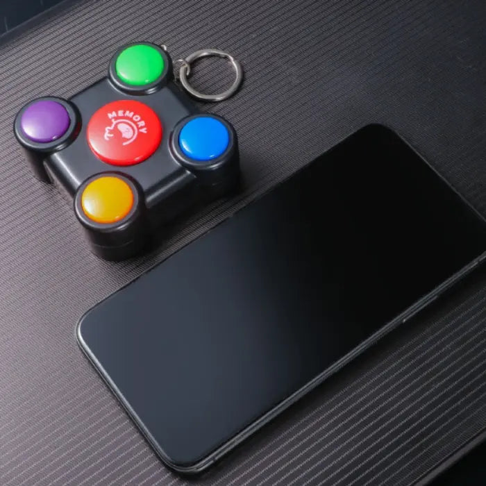 Memory game toy with keychain placed next to smartphone to show compact size.