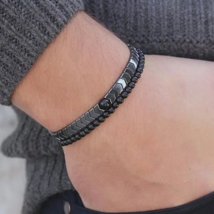 mens bracelet stack. Black beaded bracelet on a wrist with a blurred background