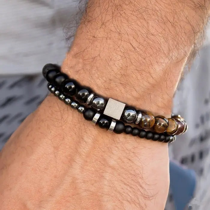 mens bracelet stack.  Close-up of a wrist wearing a black beaded bracelet with metal accents.
