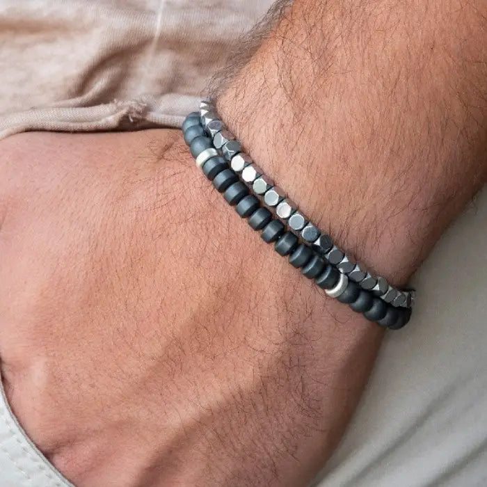 mens bracelet stack. Close-up of a wrist wearing a black beaded bracelet on a neutral background