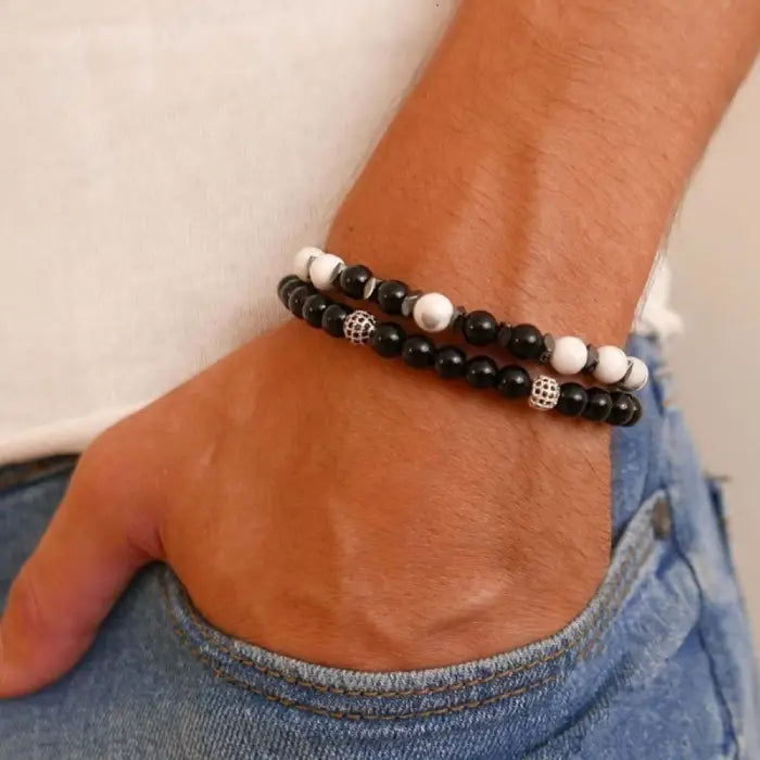 mens bracelet stack. Close-up of a wrist wearing two beaded bracelets with a neutral background