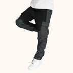 Men's dark gray and black cargo trousers paired with white sneakers, featuring side pockets