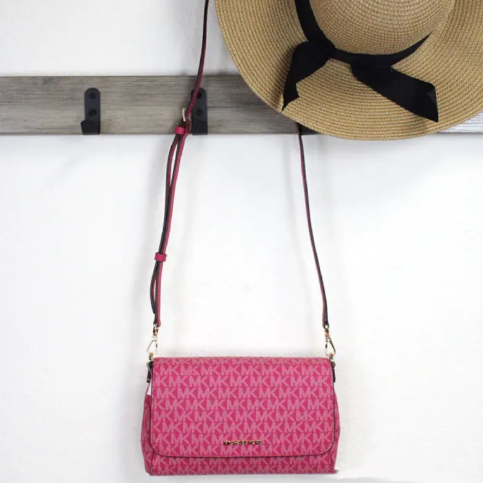 Michael Kors pink crossbody bag hanging with straw hat, perfect accessory combo for summer outings.