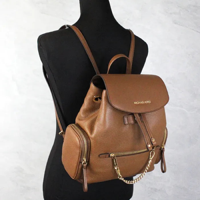 Michael Kors brown leather backpack displayed on mannequin, highlighting elegant style and logo.