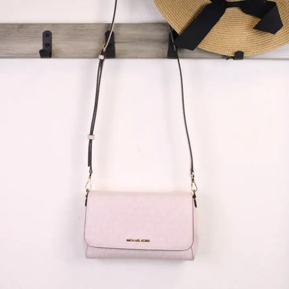 Michael Kors pink crossbody bag hanging with hat, showing versatile style and elegance.