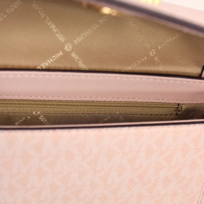 Interior of Michael Kors pink crossbody bag, featuring branded lining and zippered pocket.