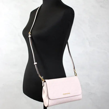 Michael Kors pink crossbody bag on mannequin, illustrating stylish wear and adjustable strap.