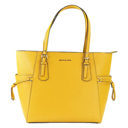 Front view of yellow Michael Kors Voyager tote featuring metal brand logo and adjustable side ties.