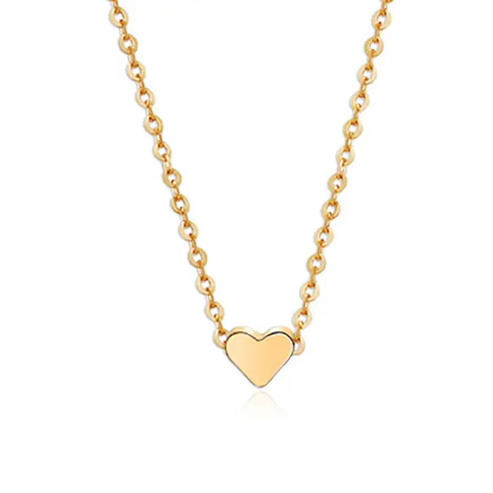 Close-up of gold heart pendant necklace on clean white surface showing chain detail