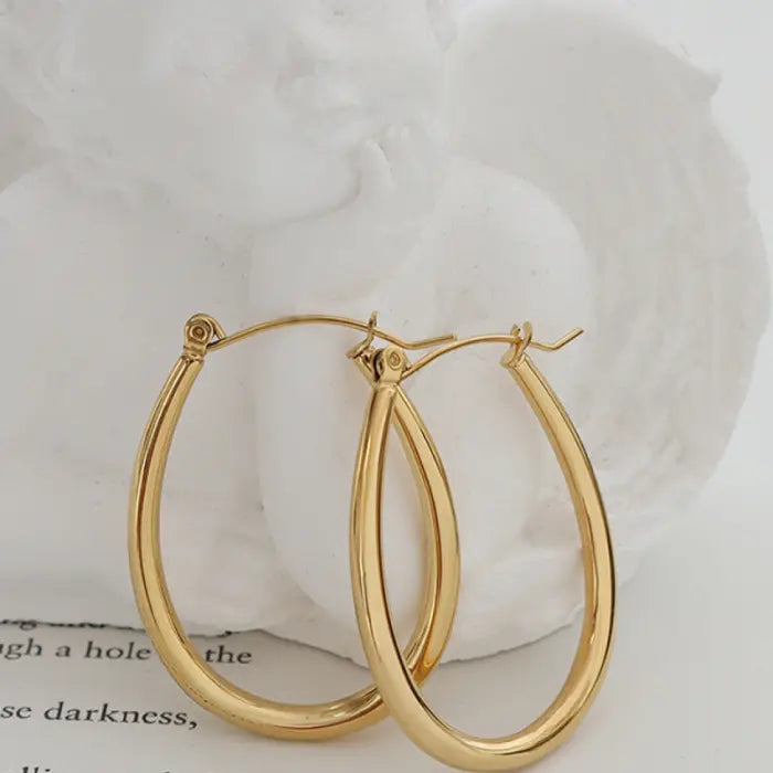 Gold oval hoops photographed on white textured background with text