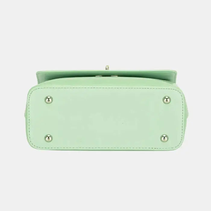 Bottom view of mint green leather handbag showcasing protective metal feet and smooth craftsmanship.