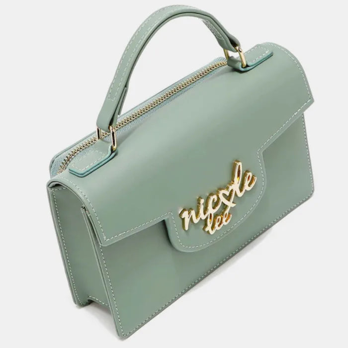 Mint green handbag with gold logo on front flap, structured shape, top handle, and zippered compartment