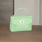  Mint green crocodile-textured handbag with silver clasp displayed on a wooden surface for style inspiration.