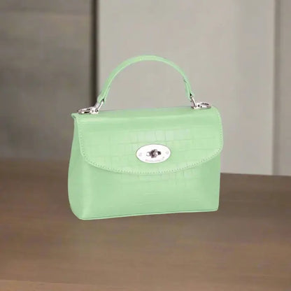  Mint green crocodile-textured handbag with silver clasp displayed on a wooden surface for style inspiration.