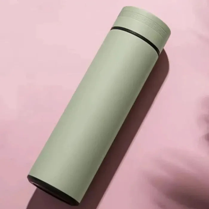 Mint green insulated water bottle with black lid ring on pink background, casting shadow