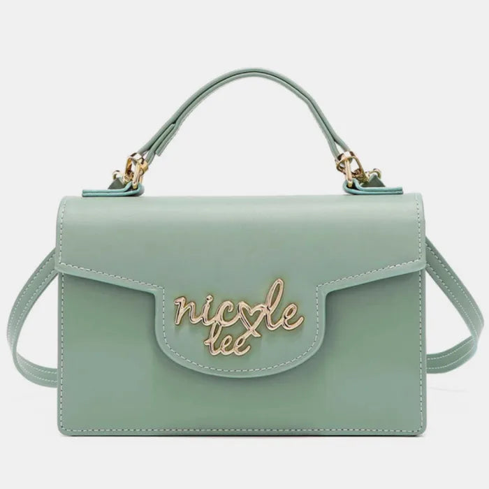 Front view of mint green handbag with gold logo on flap, top handle, and shoulder strap