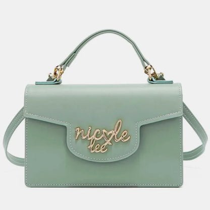 Front view of mint green handbag with gold logo on flap, top handle, and shoulder strap