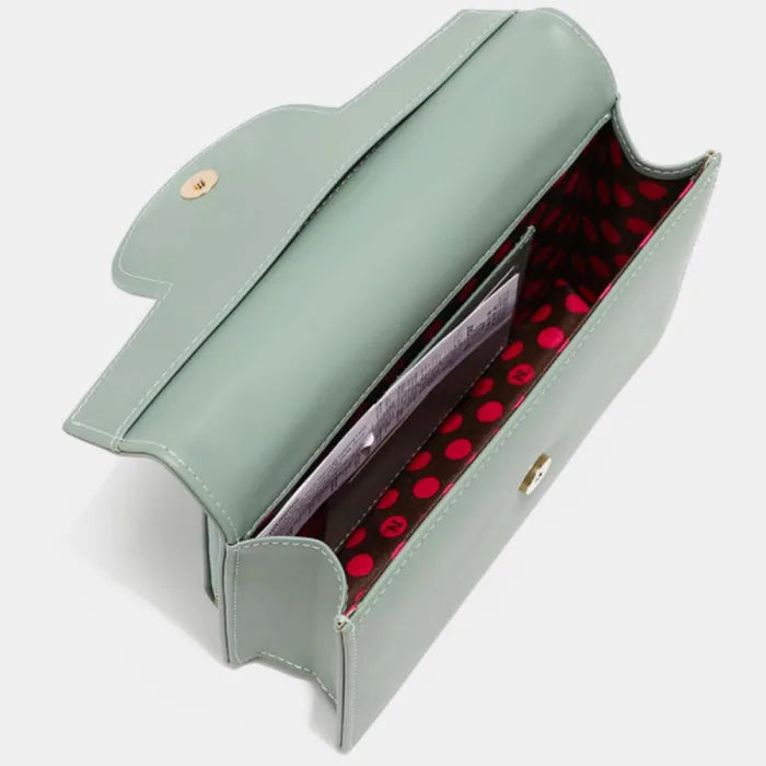 Interior view of mint green handbag with red polka dot lining and multiple compartments