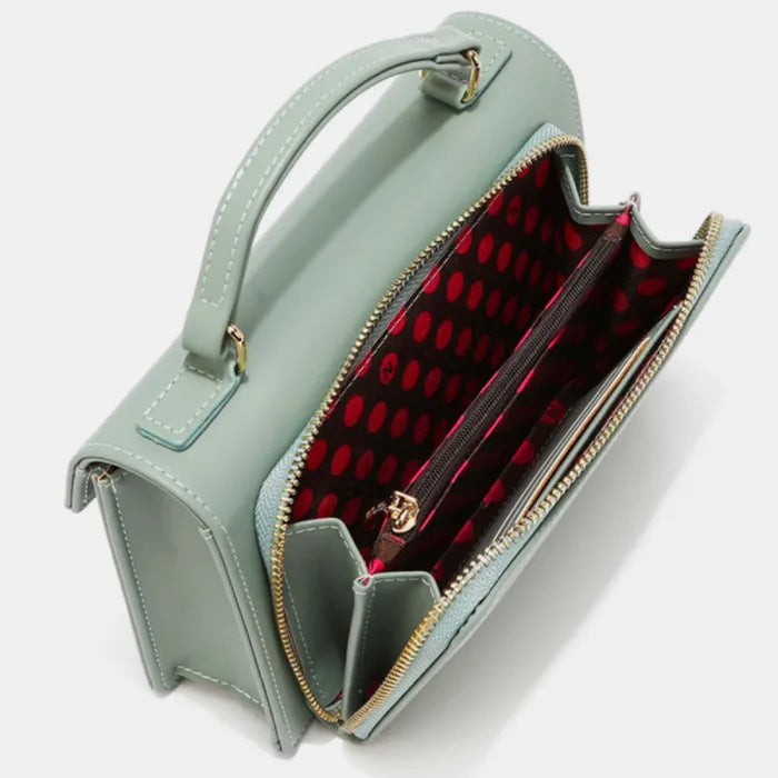 Open view of mint green handbag showing interior compartments and red polka dot lining