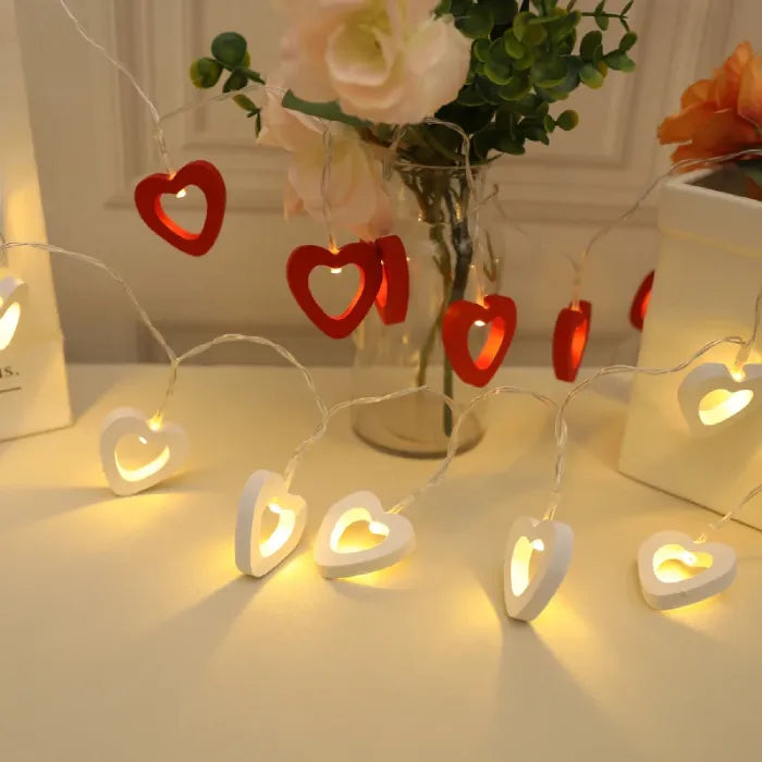 Mixed red and white heart string lights on a table with flowers for decor.