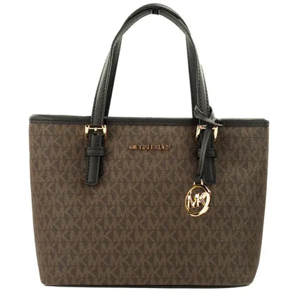 Close-up of MK brown monogram tote showing gold logo hardware and black leather straps