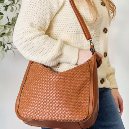 Fashion model smiling while showcasing a woven leather bag.