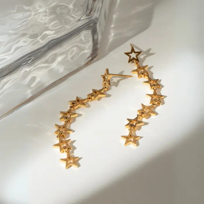 Contemporary gold star chain earrings with geometric design on white background