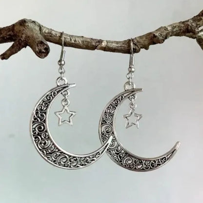 Unique silver crescent moon earrings with a star charm, perfect for celestial-themed jewelry collections.