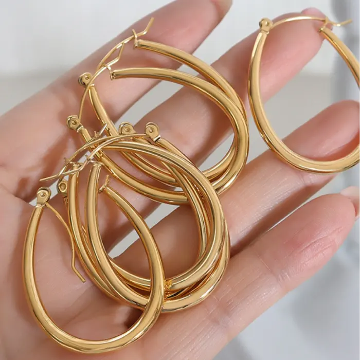 Collection of gold oval hoop earrings displayed in palm of hand