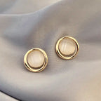 Natural white opal cat's eye earrings with smooth gold round frame, creating a soft luminous minimalist gemstone accent