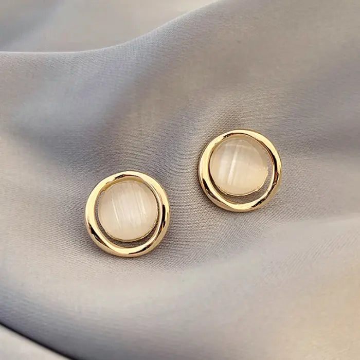 Natural white opal cat's eye earrings with smooth gold round frame, creating a soft luminous minimalist gemstone accent