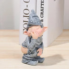 Gnome figurine with a gray outfit and hat on a light wooden surface.